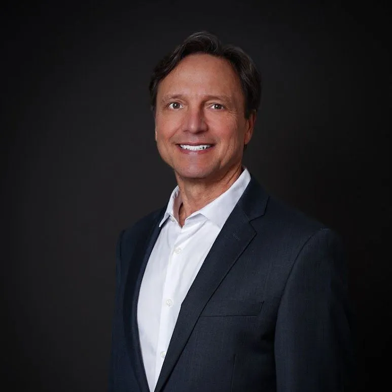 Smiling man in a suit and white shirt.