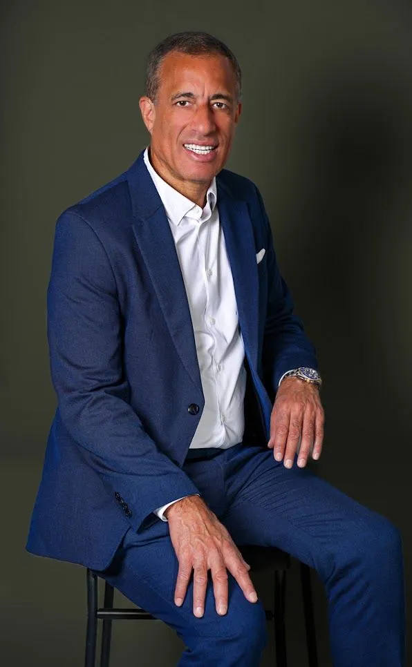 Smiling man in blue suit sitting on chair.