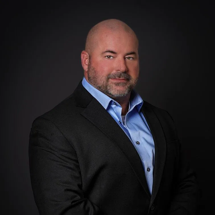 Man in black suit and blue shirt.