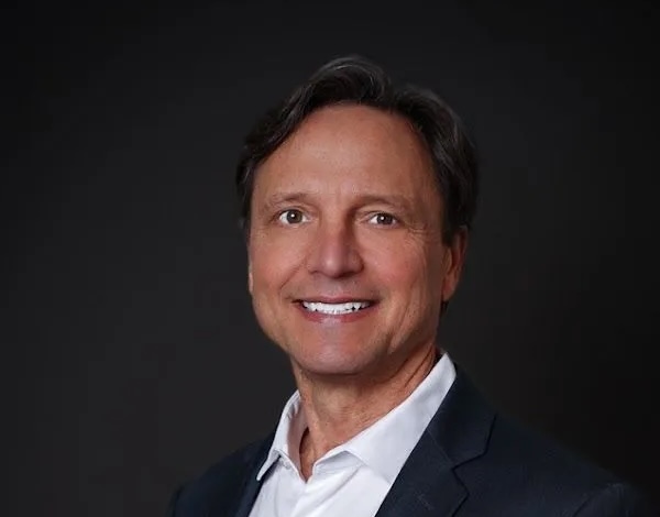 Smiling man in a suit and white shirt.