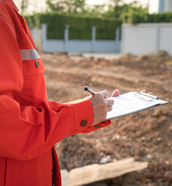 Worker in red inspecting construction site.