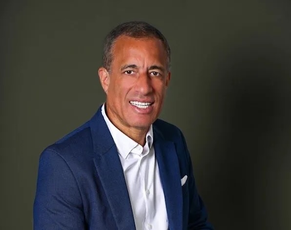 Smiling man wearing blue suit and white shirt.