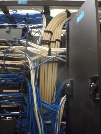 Close-up of tangled network cables in a server rack.