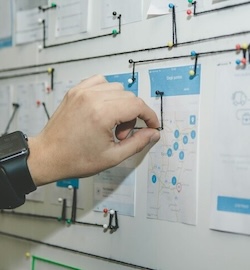 Hand pinning a paper to a whiteboard.