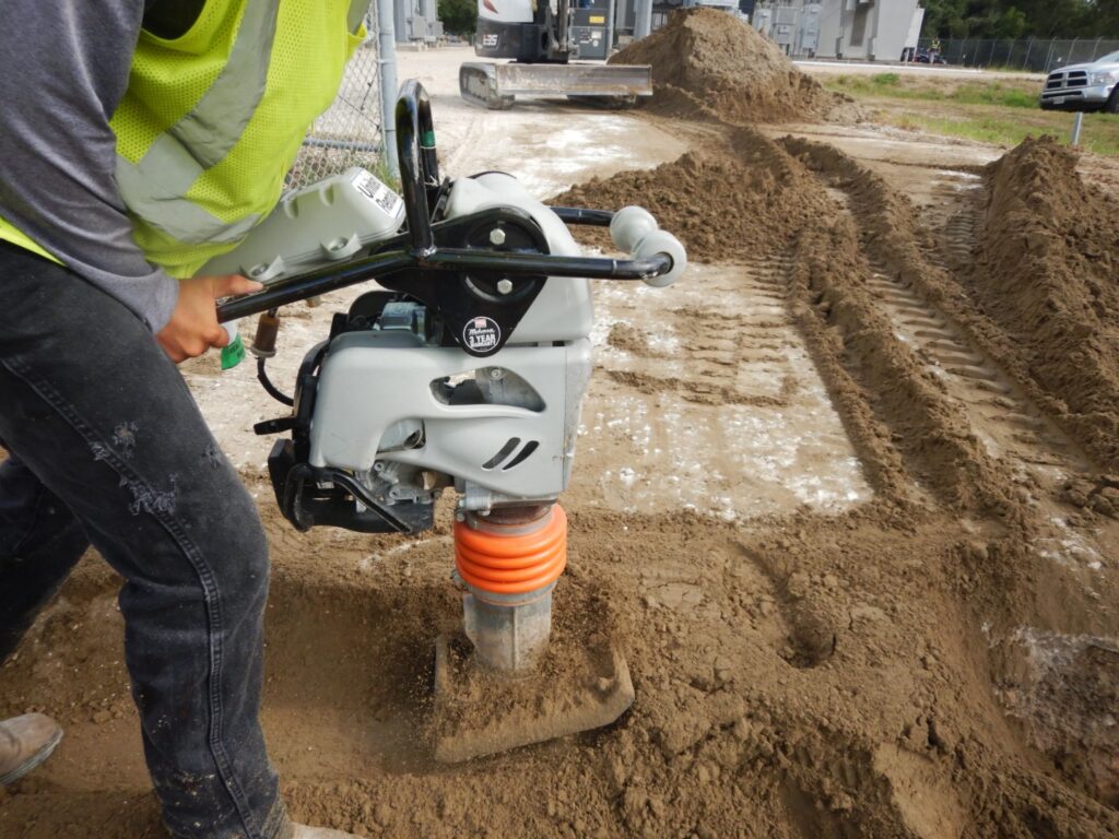 Construction worker operating a tamper.